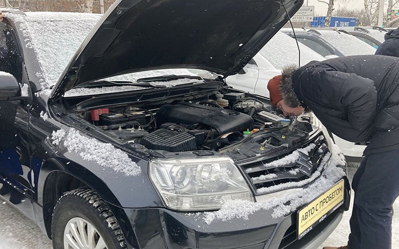 мужчина смотрит под капотом автомобиля