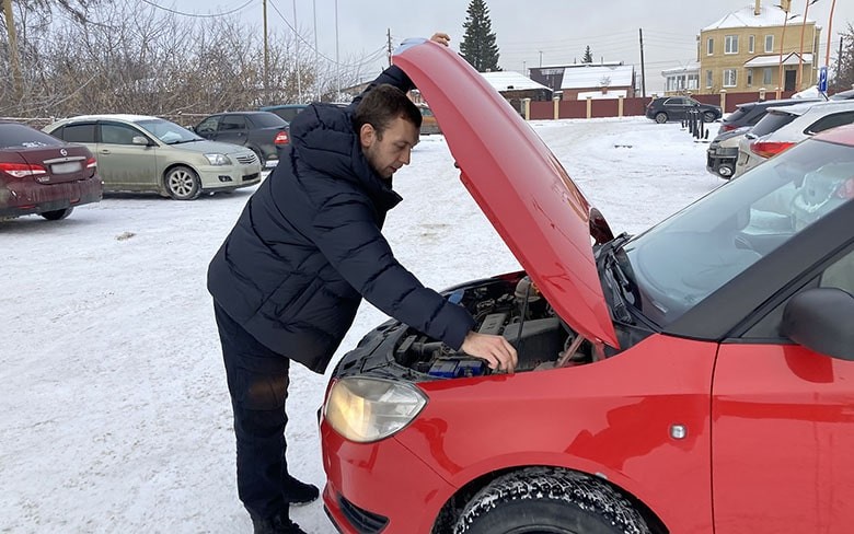 мужчина открыл капот красной машины