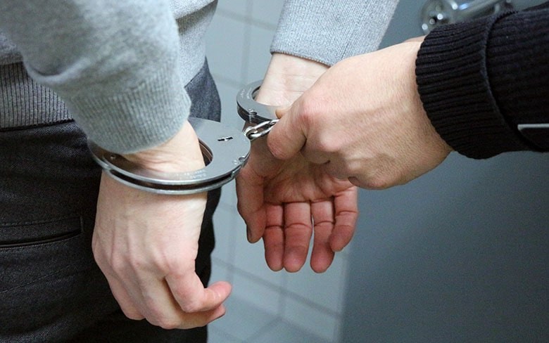 полицейский надевает наручники на задержанного
