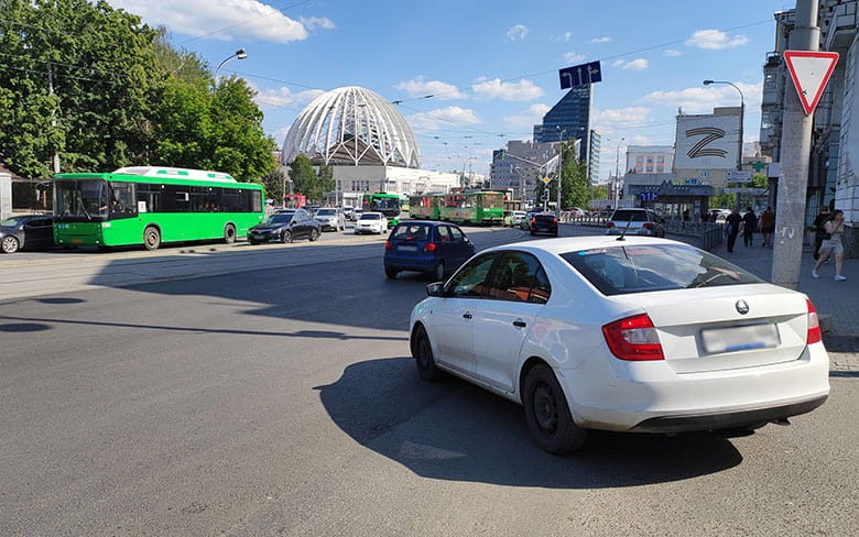 белый автомобиль поворачивает на перекрестке